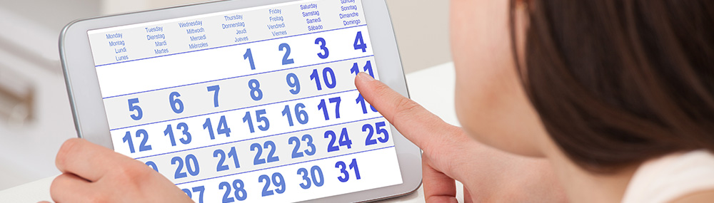 Una mujer contando días en un calendario mensual en una tableta.