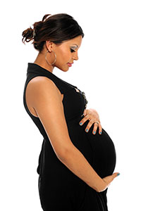 Una mujer embarazada mira hacia abajo mientras pone sus dos manos sobre su estómago.