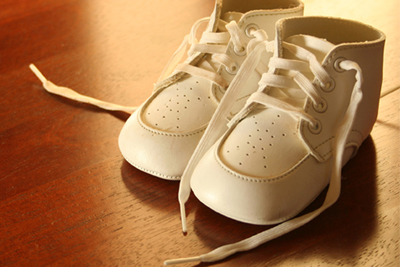 Un par de zapatos blancos de bebé sobre un suelo de madera. 