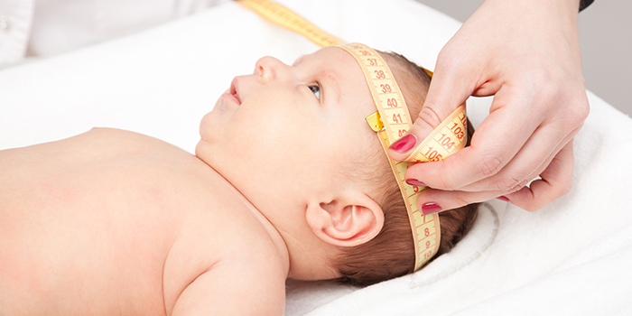 Bebé teniendo la circunferencia de la cabeza tomada con una cinta métrica.