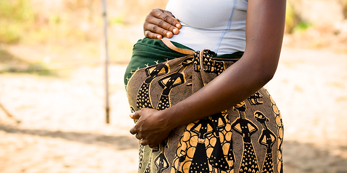 Una mujer embarazada con las manos sobre su abdomen.