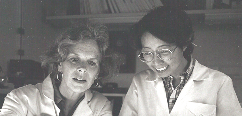 Fotografía en blanco y negro sin fecha de la joven Dra. Ozato y un colega, ambos con bata de laboratorio.