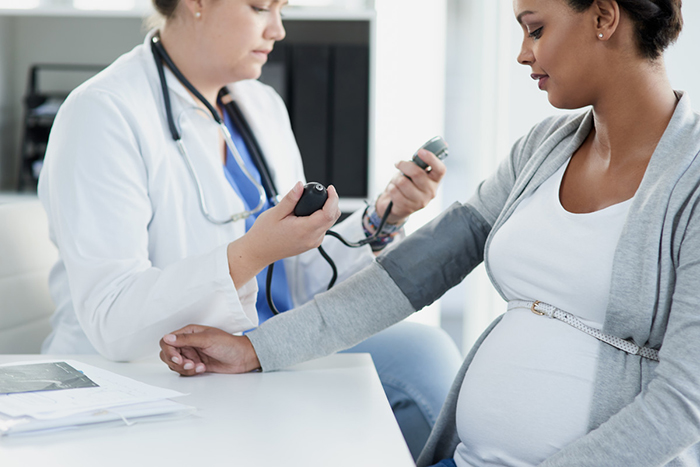 Una doctora toma la presión arterial de una mujer embarazada.
