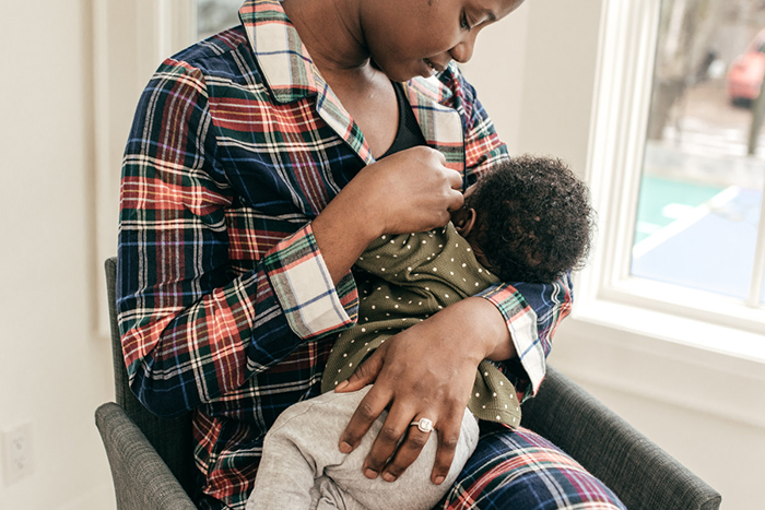 Una madre amamanta a su bebé dentro de su hogar.