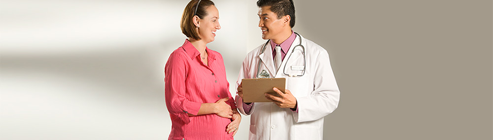Una mujer embarazada sonríe y habla con un médico.