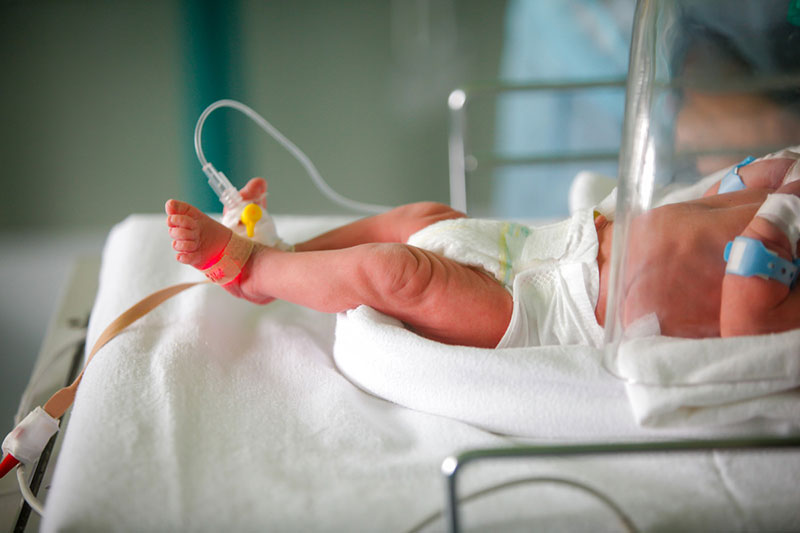 Los pies y el torso de un bebé son visibles en un entorno hospitalario.