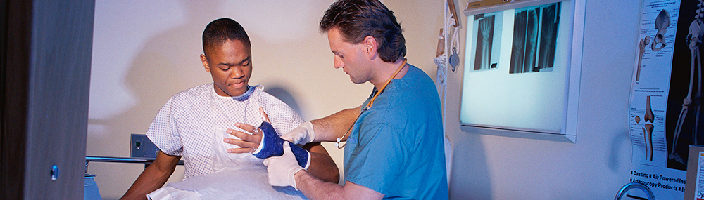 Un proveedor de servicios de salud examina a un paciente adulto joven con un yeso en la muñeca.