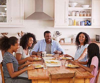 Los padres y sus tres hijos sentados a la mesa de la cocina comen juntos.