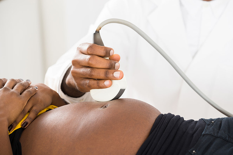 La mano del médico moviendo la ecografía en el vientre de una mujer embarazada.