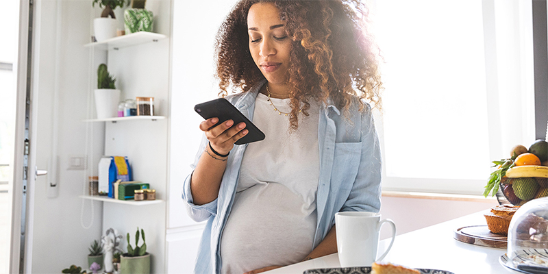 Persona embarazada sosteniendo un dispositivo móvil.
