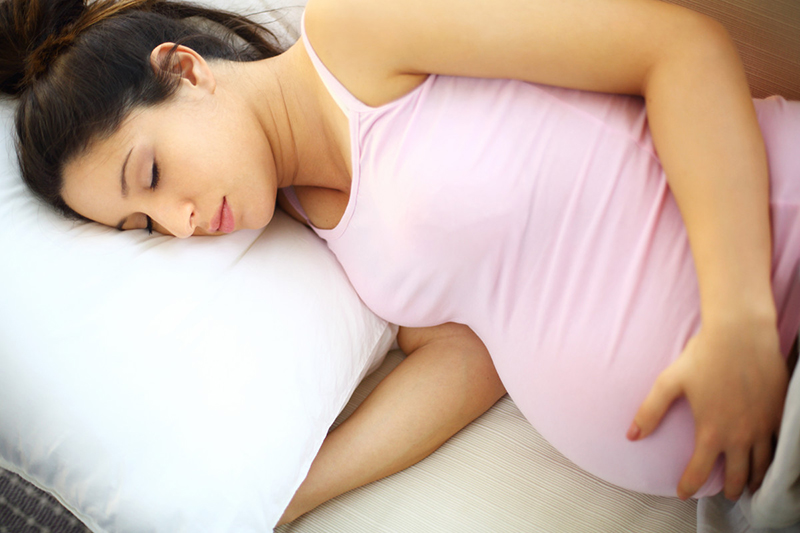 Persona embarazada durmiendo de lado.