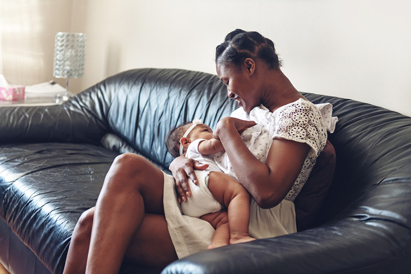 Mujer sentada en un sofá amamantando a un bebé.