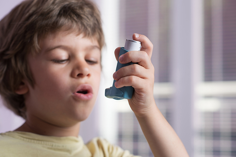 Niño usando un inhalador para el asma.
