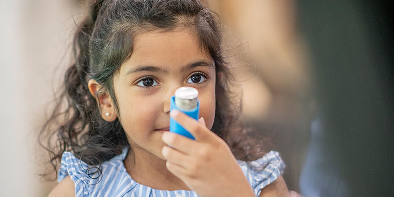 Niño sujetando un inhalador para el tratamiento del asma.