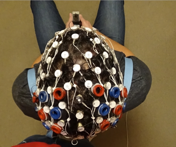 Vista panorámica de la parte superior de la cabeza de una persona. El gorro, que cubre toda la cabeza, tiene nodos de color blanco, rojo o azul.