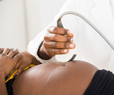 Ultrasonido en movimiento de la mano del médico en el vientre de una mujer embarazada
