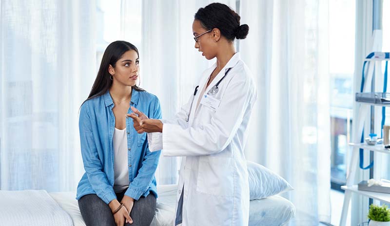 Una mujer habla con su profesional de salud durante un chequeo.