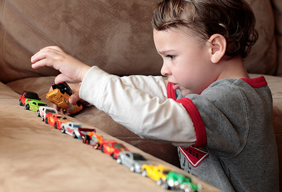 Un niño jugando con autos de juguete.