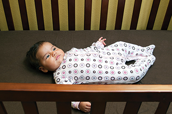 Imagen de un bebé que está acostado boca arriba en una cuna.