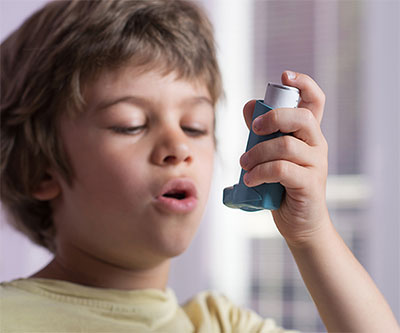 Un niño sostiene un inhalador para el asma en la mano.