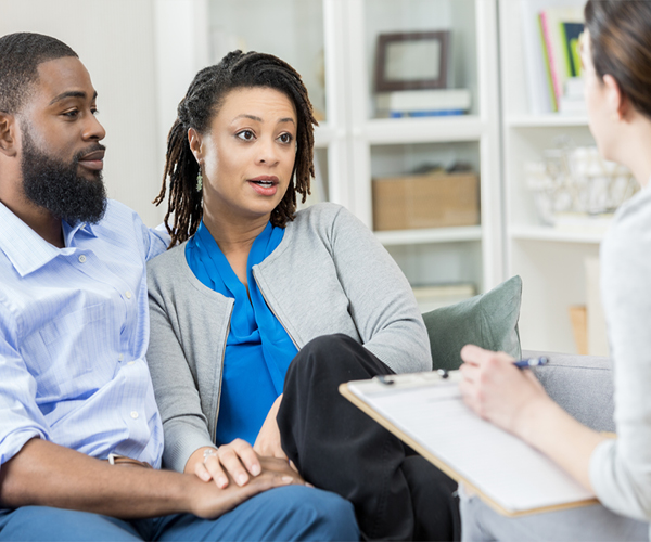 Imagen de una pareja afroamericana hablando con un proveedor de atención médica, que sostiene un portapapeles.