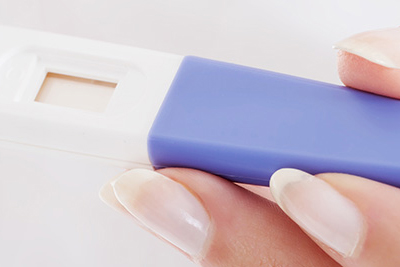Una mano de mujer sostiene una prueba de embarazo.